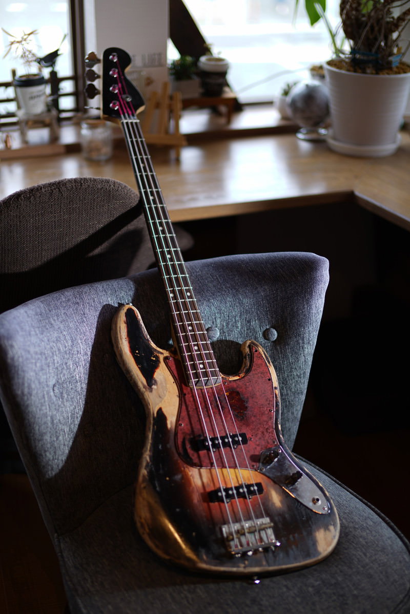 カフェのテーブルに置かれた赤いピックガードのエレキベース