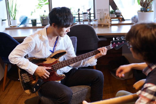 ベースギターの指導を受ける男性生徒の演奏フォーム習得レッスン