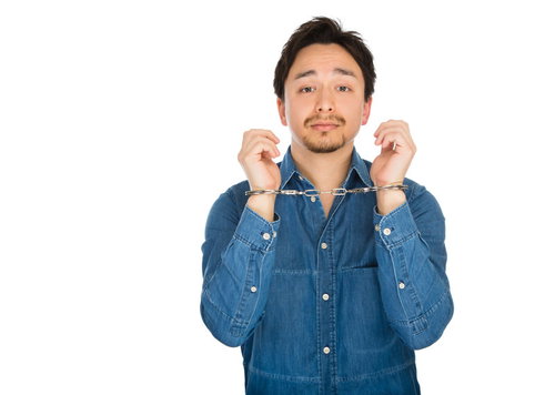 手錠を掲げるスーツ姿の女性