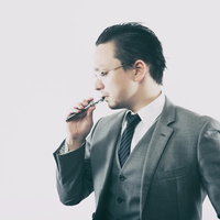 フレーバーを楽しむビジネスマンの電子タバコの写真