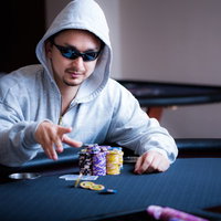 ポーカーテーブルでチップを払うサングラスをかけたギャンブラーの写真