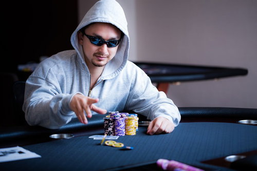 ポーカーテーブルでチップを払うサングラスをかけたギャンブラー