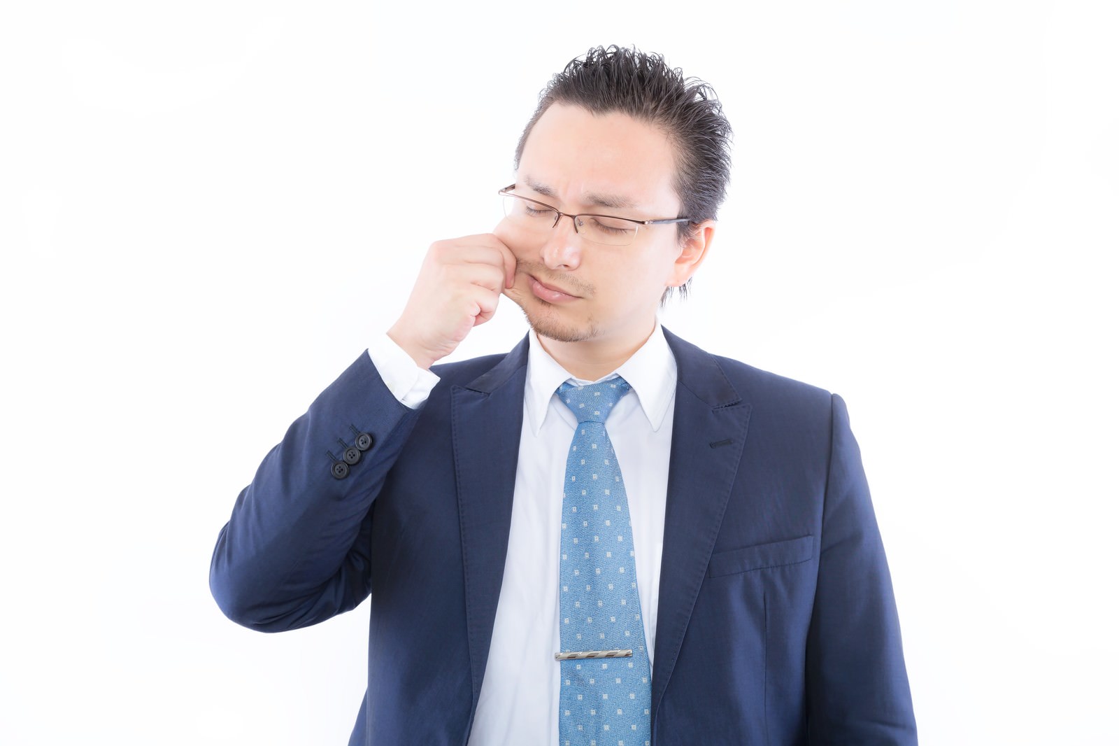 頬をつねるスーツ姿の眼鏡の男性［モデル：Max_Ezaki］