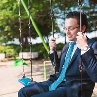 ノスタルジックな表情の外資系サラリーマンがブランコに座るの写真