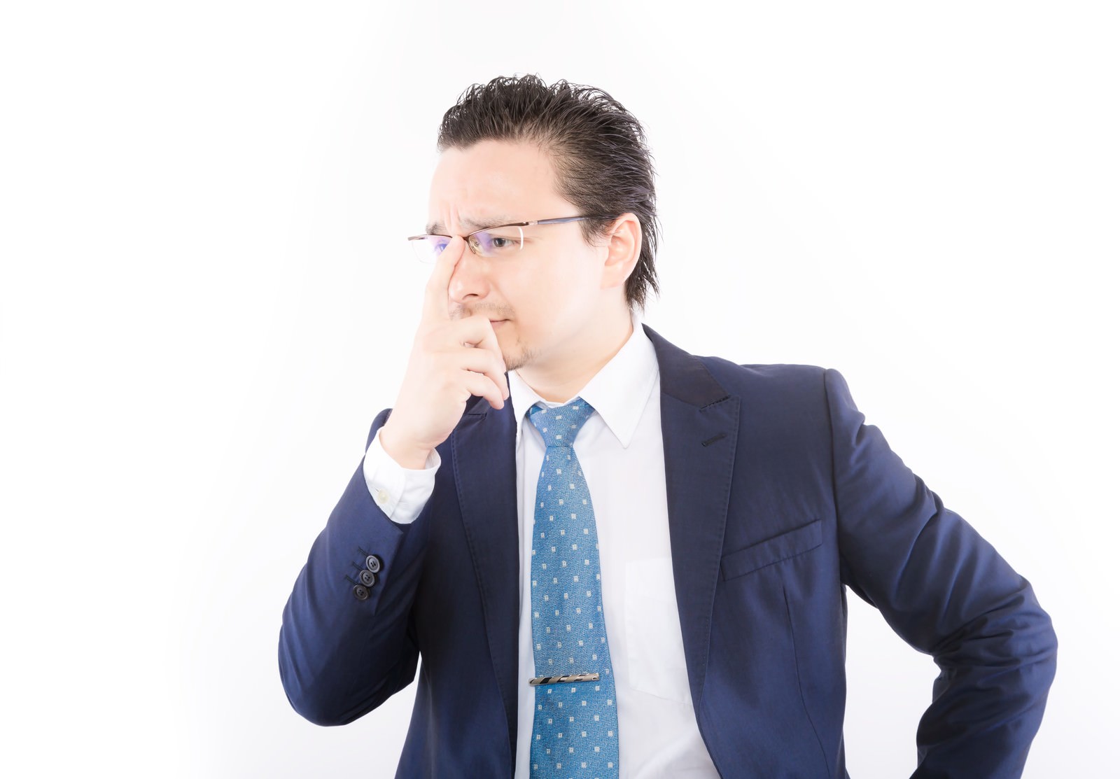 鼻を押さえ考え込むスーツ姿の男性［モデル：Max_Ezaki］