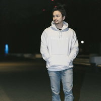 白いパーカーを着て夜の街を散歩するドイツ人ハーフの男性の写真