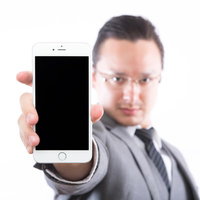 スマートフォンの画面を提示するエンジニア男性の写真