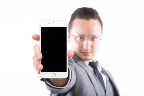 スマートフォンの画面を提示するエンジニア男性