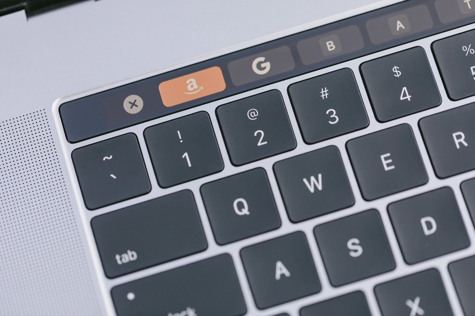 MacBookのタッチバーに表示されたAmazonロゴとキーボード