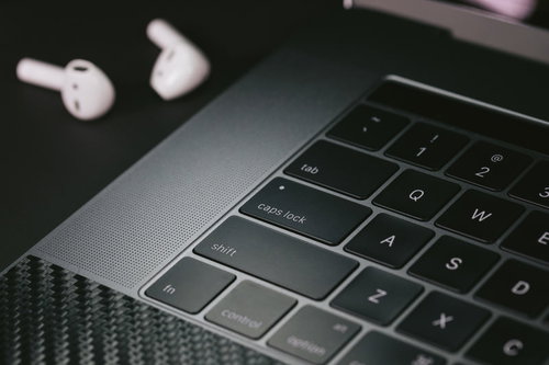 ノートパソコンとワイヤレスイヤホンのデスクセットアップ