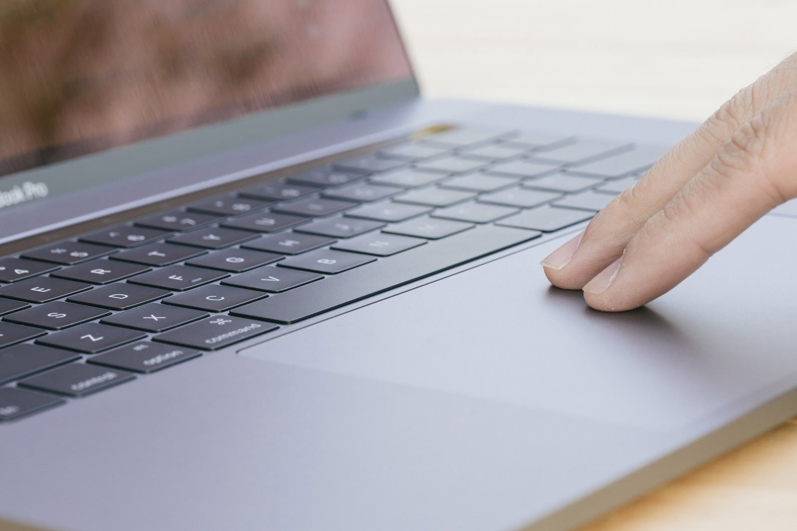 MacBook Proのトラックパッドに指を置いて操作する手元