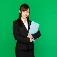 グリーンバック背景で書類を持ったスーツ姿の女性の写真