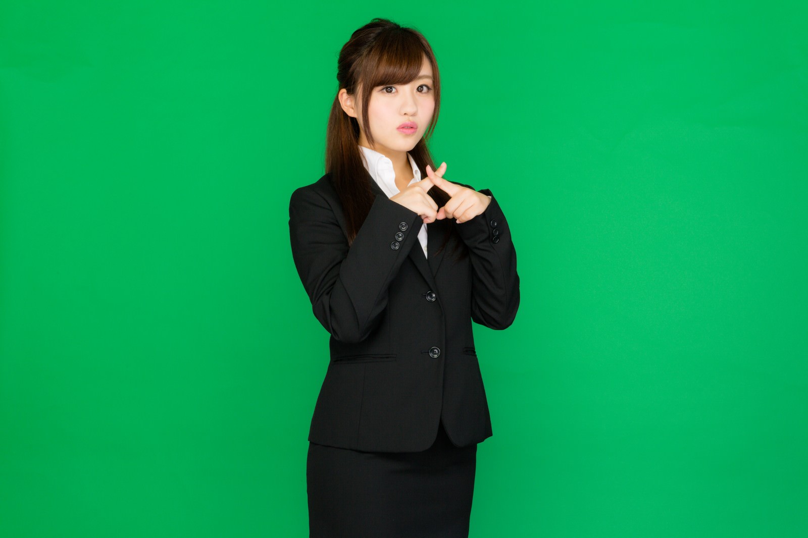グリーンバックで両手バツポーズをするスーツ姿の女性［モデル：河村友歌］