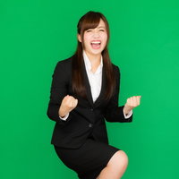 社内プレゼンが通って喜ぶスーツ姿の女性、ガッツポーズ（グリーンバック）の写真