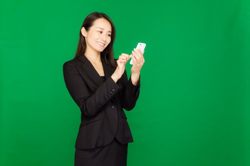 スマートフォンで今夜の飲み会をアプリで予約する女性（グリーンバック）