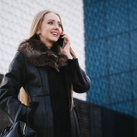 黒いコートを着て電話するセレブ女性の写真