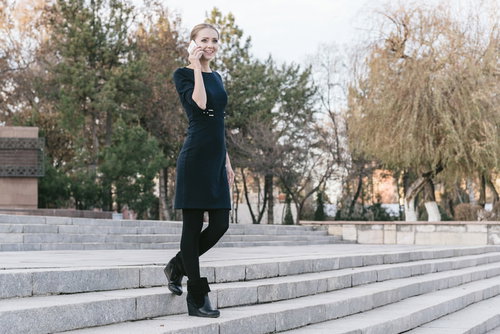 石段に座って外で電話するスマホを持つ外国人女性モデル