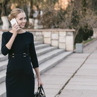 屋外でスマートフォンの通話中に微笑むブロンドモデルの写真