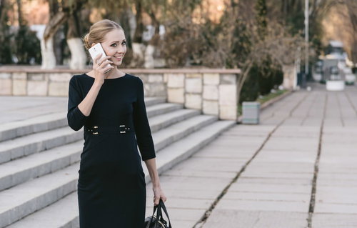 屋外でスマートフォンの通話中に微笑むブロンドモデル