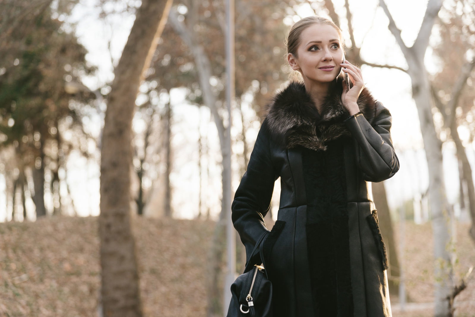 黒いコートを着た女性がスマートフォンで通話している［モデル：モデルファクトリー］