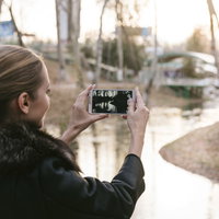 公園でスマートフォンを使って景色を撮影するブロンド美女の写真