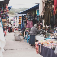 ボリビアの街角の露店商店街：カラフルな民族衣装と織物が並ぶ市場風景の写真