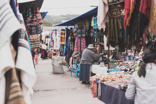 ボリビアの街角の露店商店街：カラフルな民族衣装と織物が並ぶ市場風景