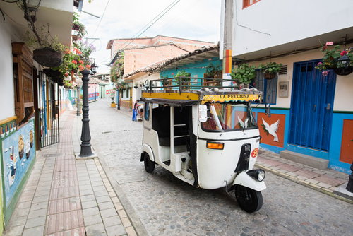 南米のカラフルな街並みを走る白いトゥクトゥク