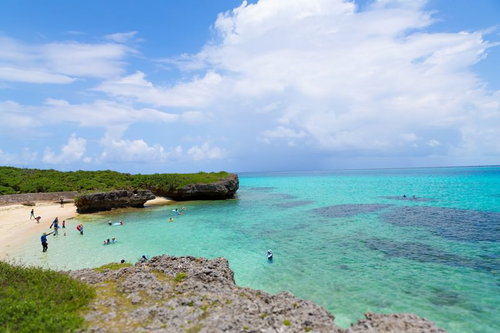 白い砂浜と岩場の浅瀬で泳ぐ人たちのシュノーケリングスポット