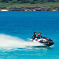 白い水しぶきを上げて水面を走る2人乗りのジェットスキーの写真