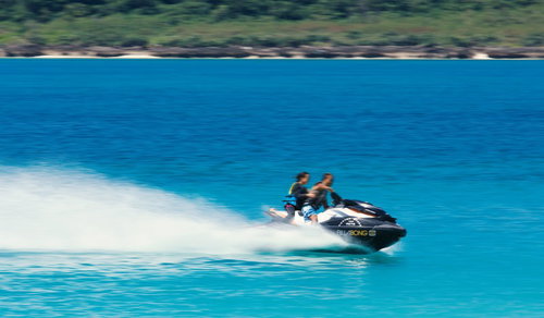 白い水しぶきを上げて水面を走る2人乗りのジェットスキー