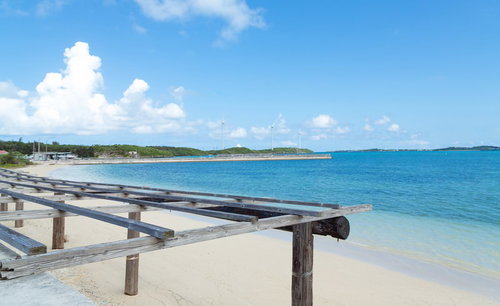 青い海と遠くの島が見える遠浅の砂浜と木の日除け骨組み