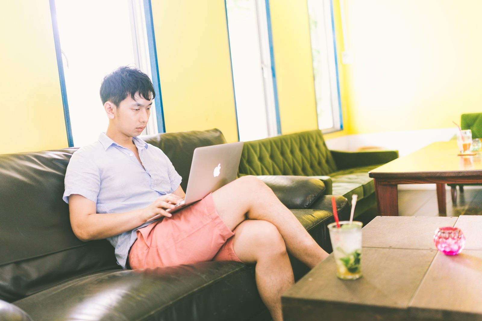 カフェのソファーでMacBookを操作する男性［モデル：大川竜弥］