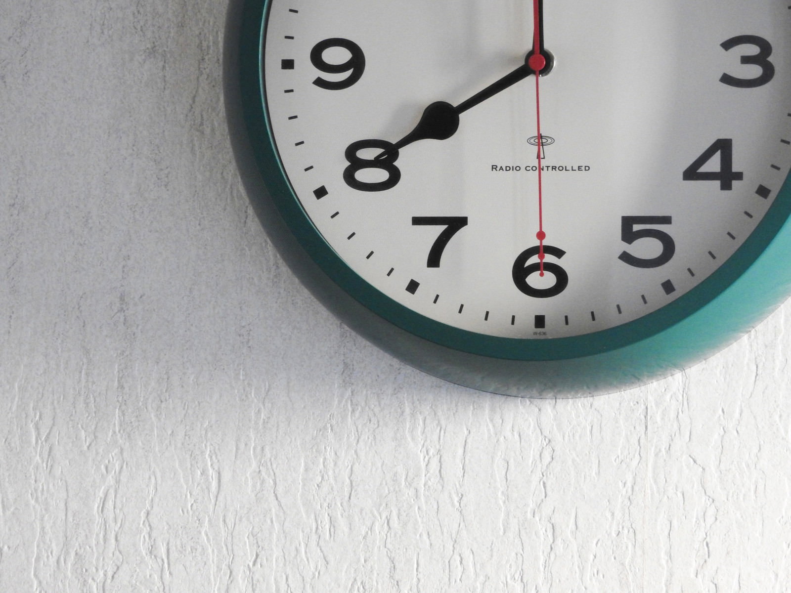 白い壁に掛けられた8時を指すアナログの壁掛け時計