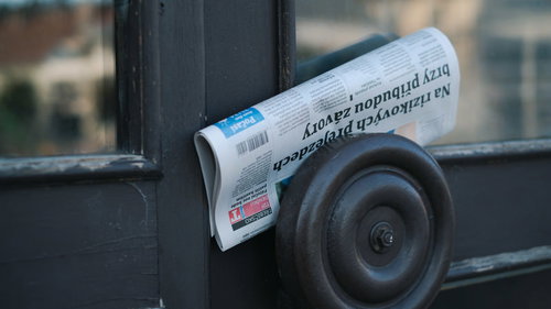 チェコの玄関ドア取っ手に挟まれた配達新聞紙