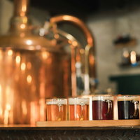 本場チェコの色の違うビール、銅製の醸造タンクを背景にした飲み比べの写真