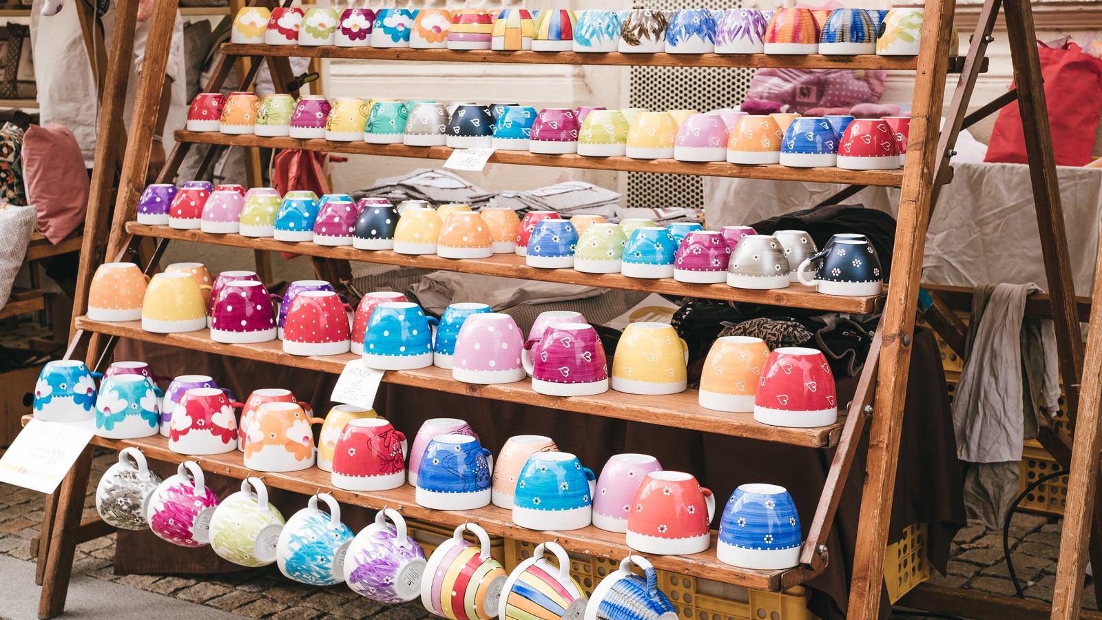 木製の棚に赤や青など色とりどりのカップが並ぶ出店の様子
