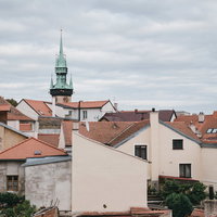 チェコ・ズノイモ市の住宅街に立つ緑色の尖塔の時計台の写真