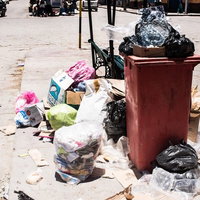 ゴミ箱から溢れ出す投棄物と散乱する廃棄物の写真