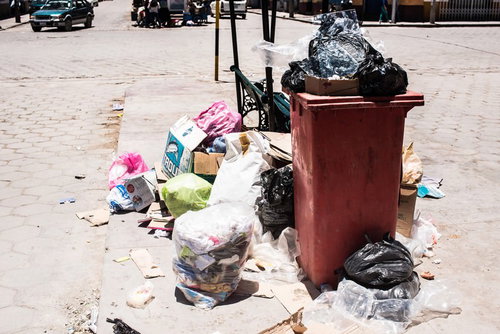 ゴミ箱から溢れ出す投棄物と散乱する廃棄物
