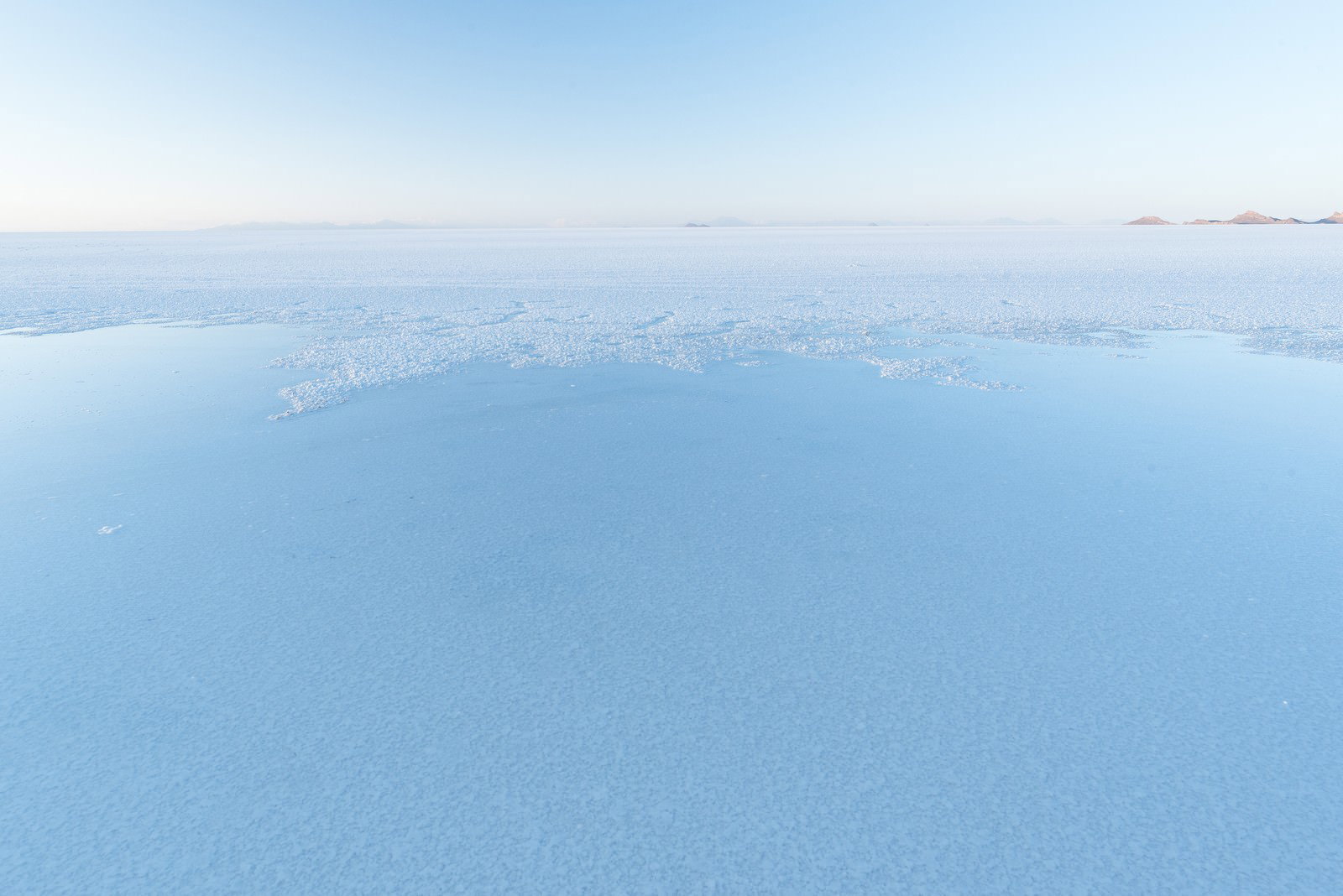 ウユニ塩湖の雨季、島影が映る広大な水面と空の風景