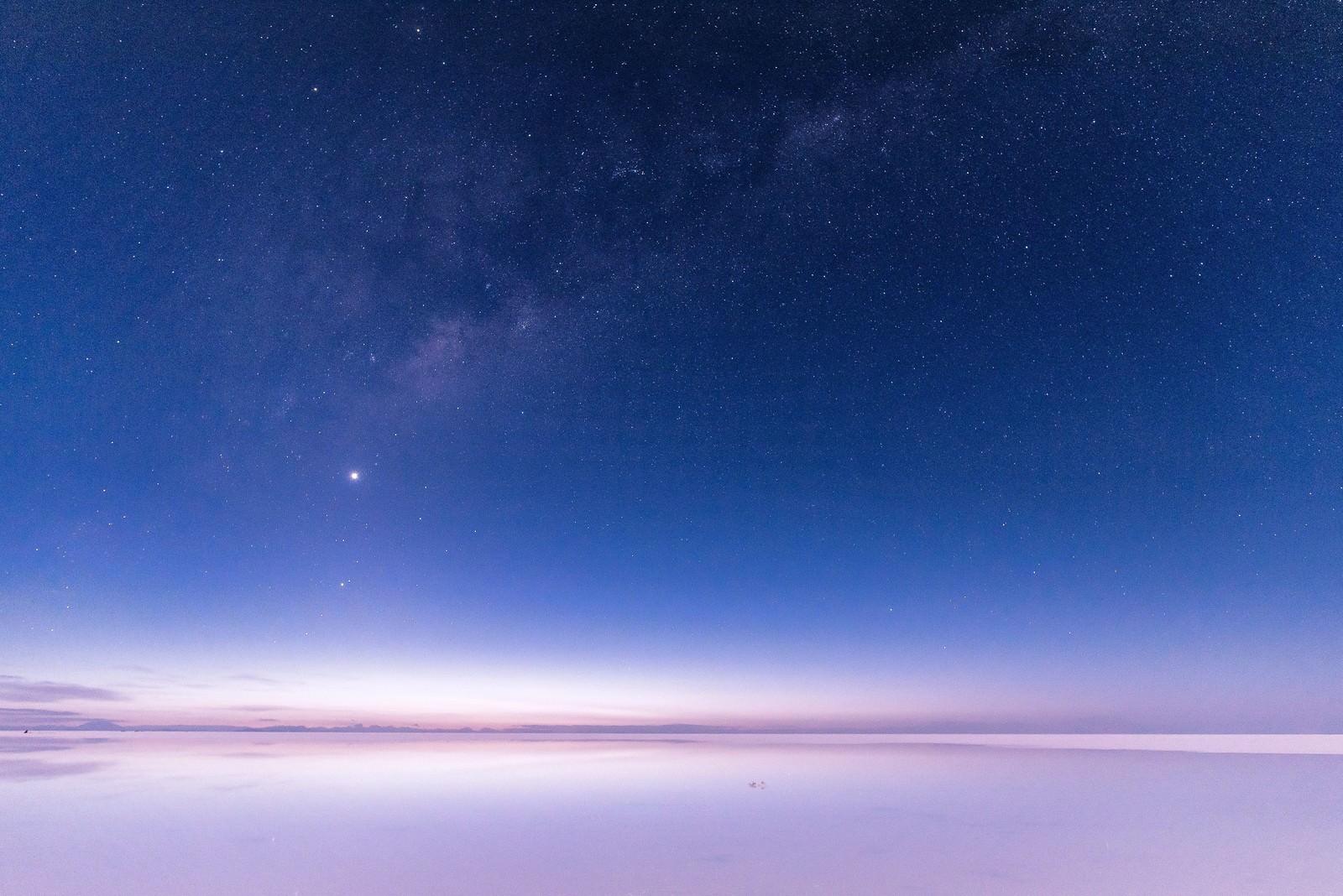 ウユニ塩湖の夜空に無数の星と金星が輝き、塩湖に映る星空
