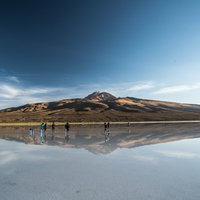 ウユニ塩湖に訪れた観光客と鏡のように映り込む火山の写真