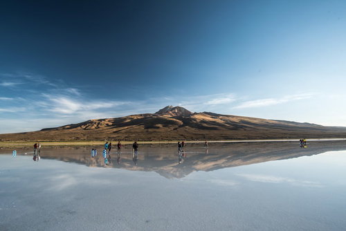 Tourists at Uyuni Salt Flats with Mountains Reflected Like a Mirror