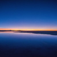天空の鏡に映る朝焼けのウユニ塩湖：明け方の絶景の写真
