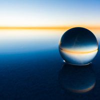 丸い水晶球に映るウユニ塩湖の水平線と夕焼けの写真