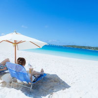 白い砂浜のビーチチェアで宮古ブルーを堪能するカップルの写真