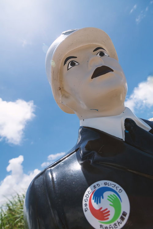 下から見上げた白い肌と黒い服の宮古まもる君の像