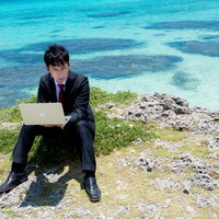 宮古ブルーをバックに新規プロジェクトの企画書を作成するIT戦士の写真