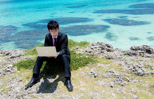 宮古ブルーをバックに新規プロジェクトの企画書を作成するIT戦士